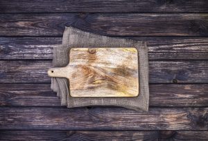 Cutting board on dark wood background, top view