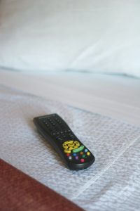 A hotel remote sitting on a plush bed.